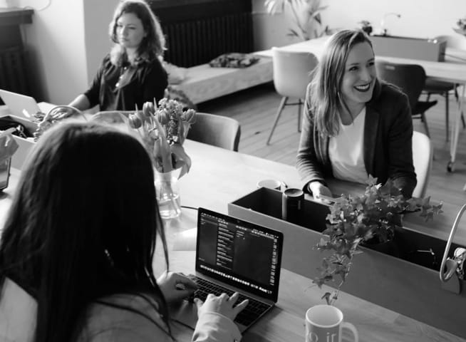 three women discussing with laptops on table